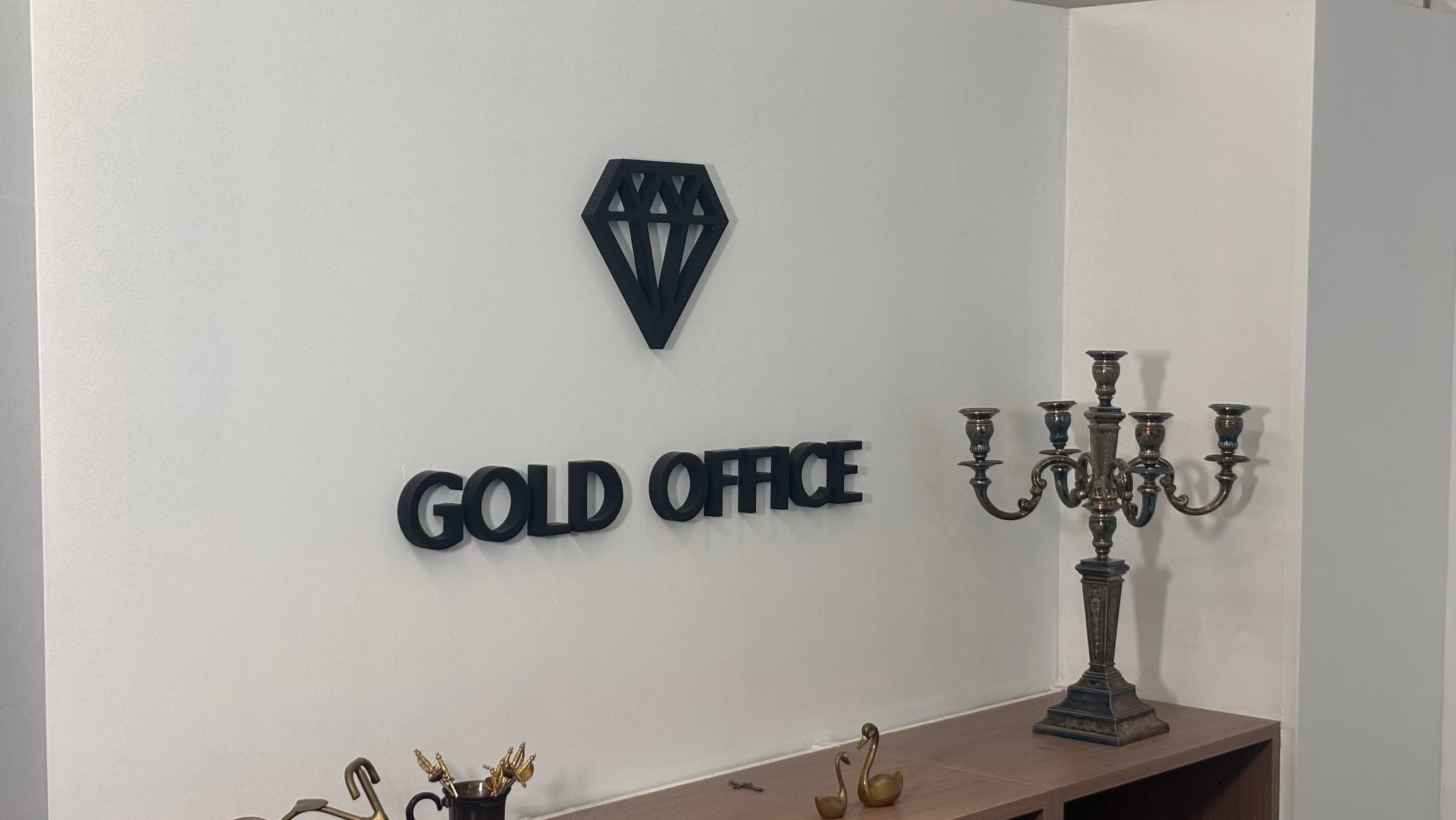 Het interieur van Gold Office in Overijse, met de naam aan de muur en antiek zilverwerk in de kast